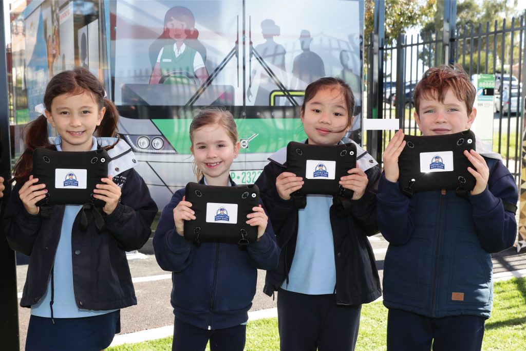 kids holding tablets in front of bus