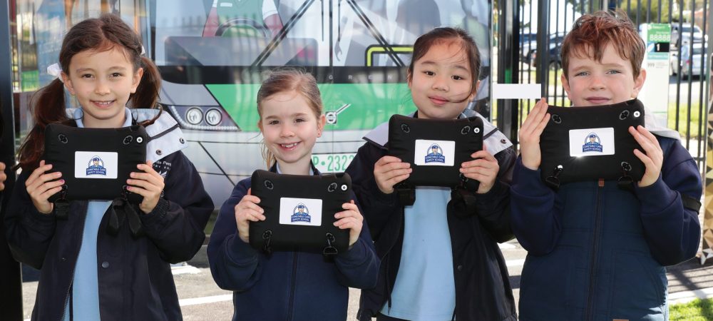 kids holding tablets in front of bus